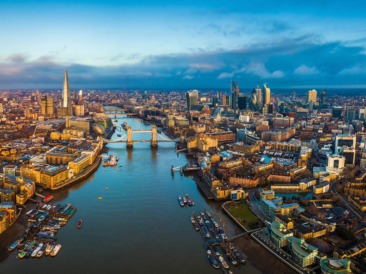 Golden hour aerial view of London’s skyline, including the Tower Bridge and famous skyscrapers.