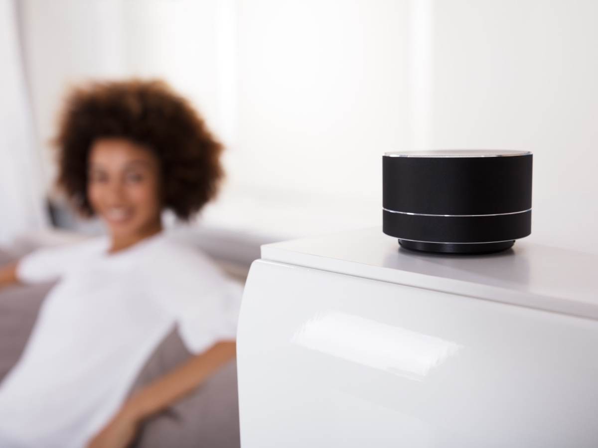 Close up of smart speaker with woman in blurred background