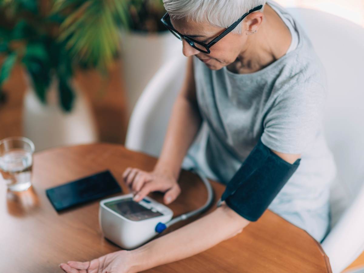 Woman measuring blood pressure and checking parameters via smartphone