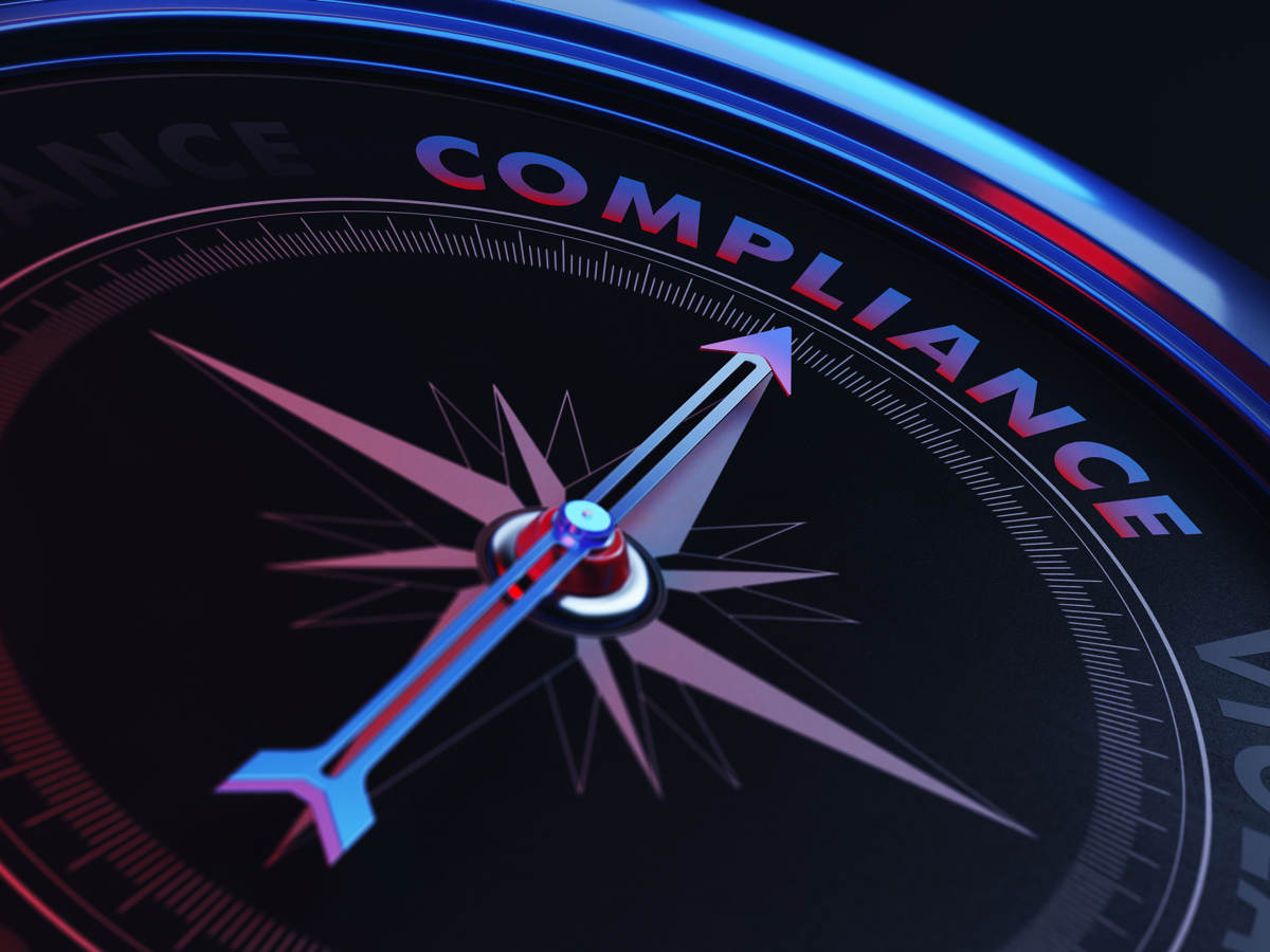 The arrow of a compass pointing toward the word compliance.