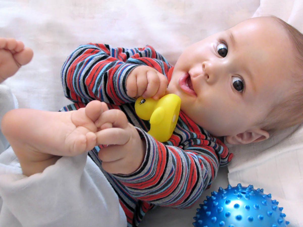 Baby lying down playing with toys