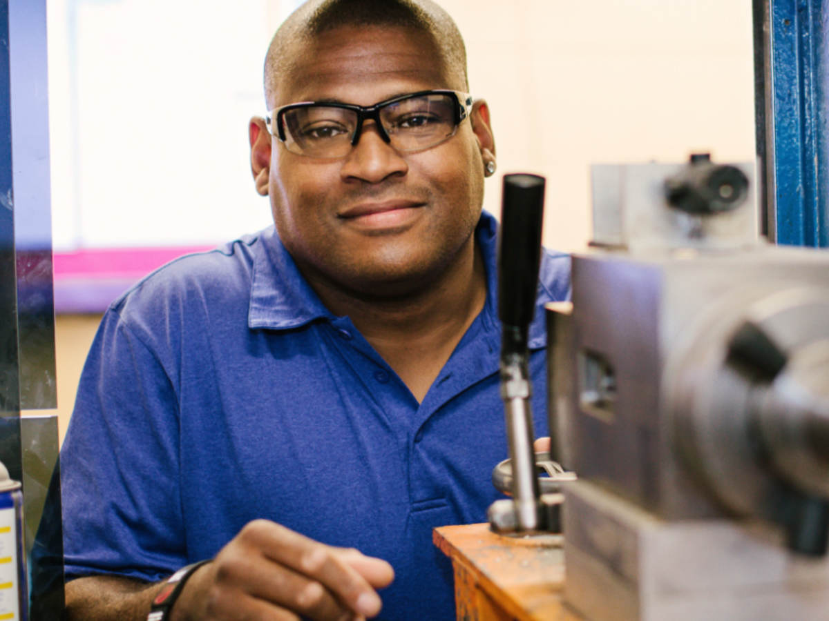 An African American male ballistics laboratory technician smiles