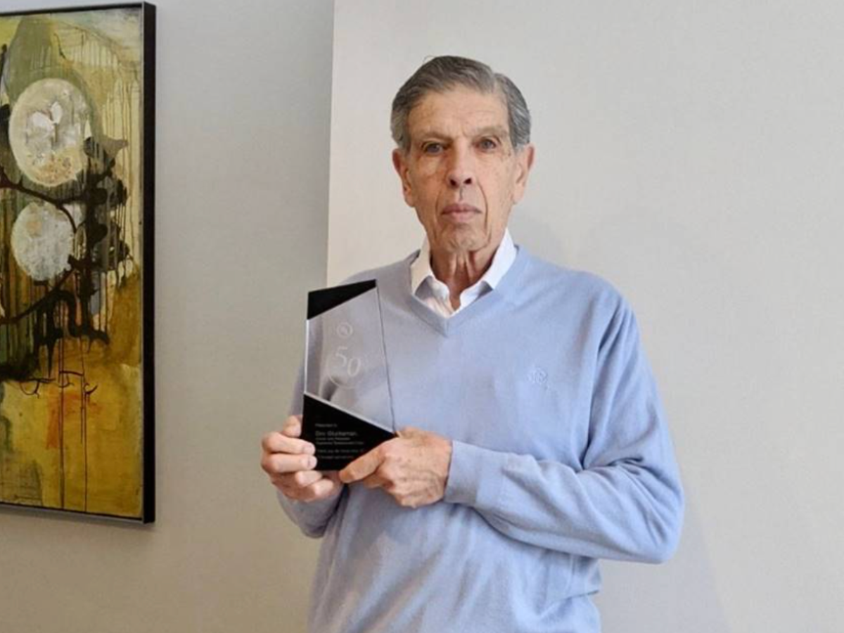 Image of Dov Glucksman holding his commemorative award for 50-years of loyalty.