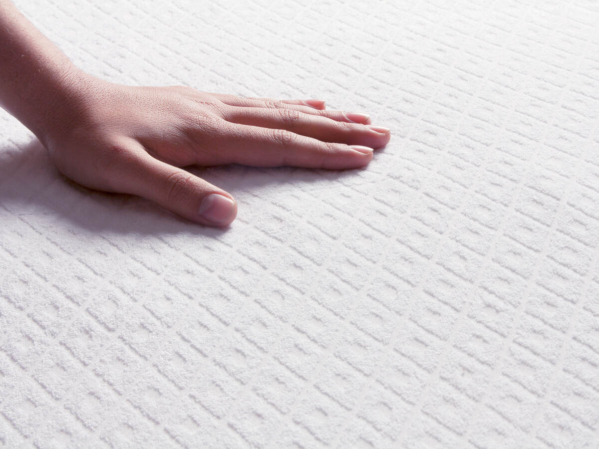 Human hand touching a mattress top