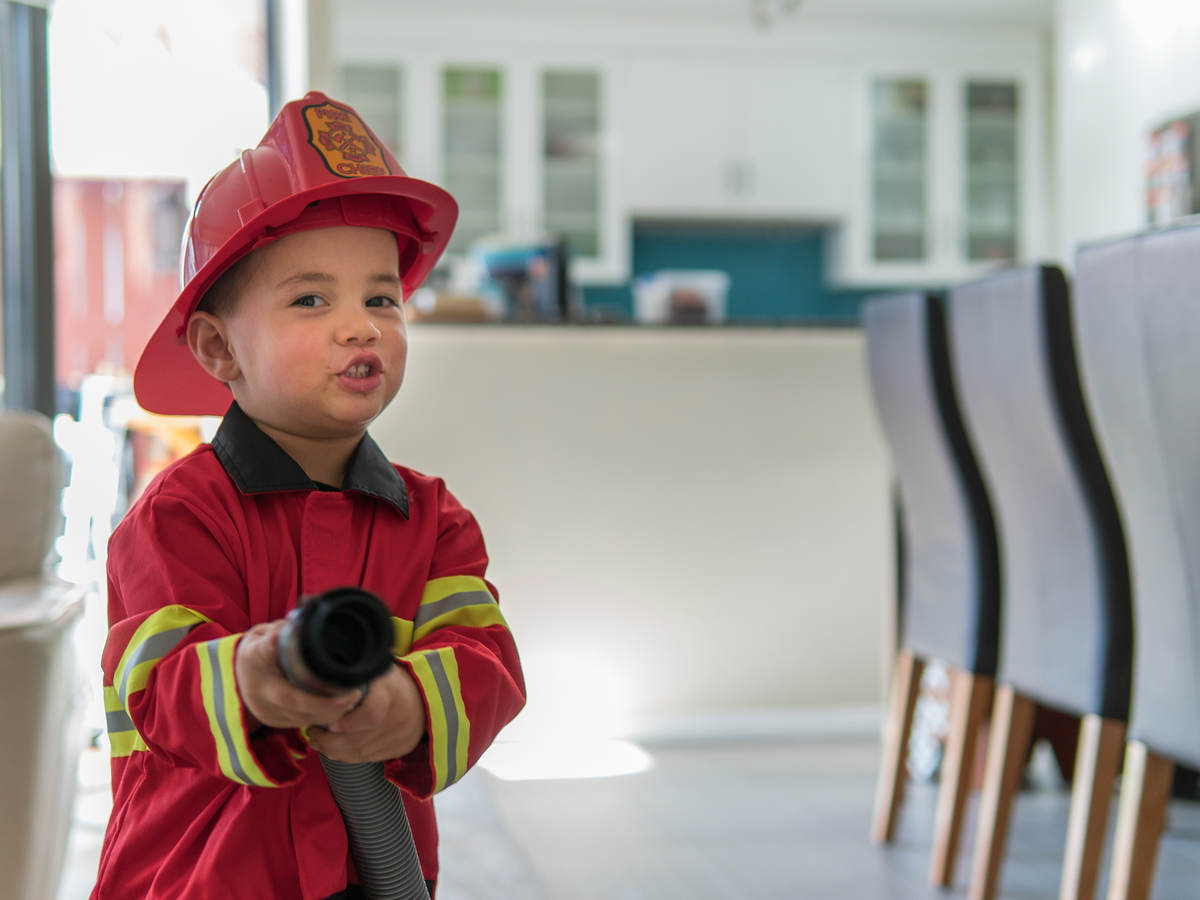 Child dressed like a fireman holding a hose