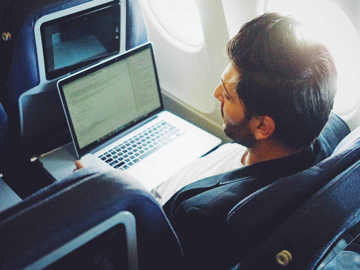 Man using a laptop on an airplane