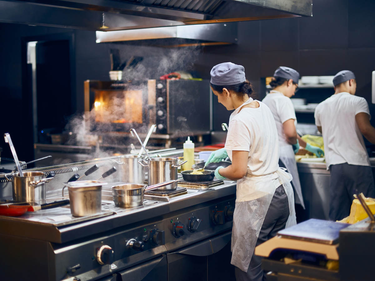 the team of cooks backs in the work in the modern kitchen, the workflow of the restaurant in the kitchen.