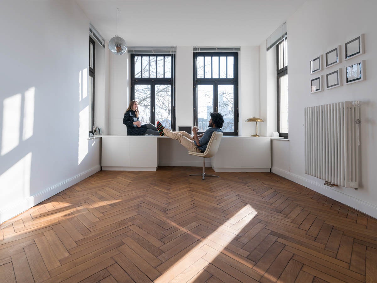 Woman and man in sparsely furnished room with hardwood floors