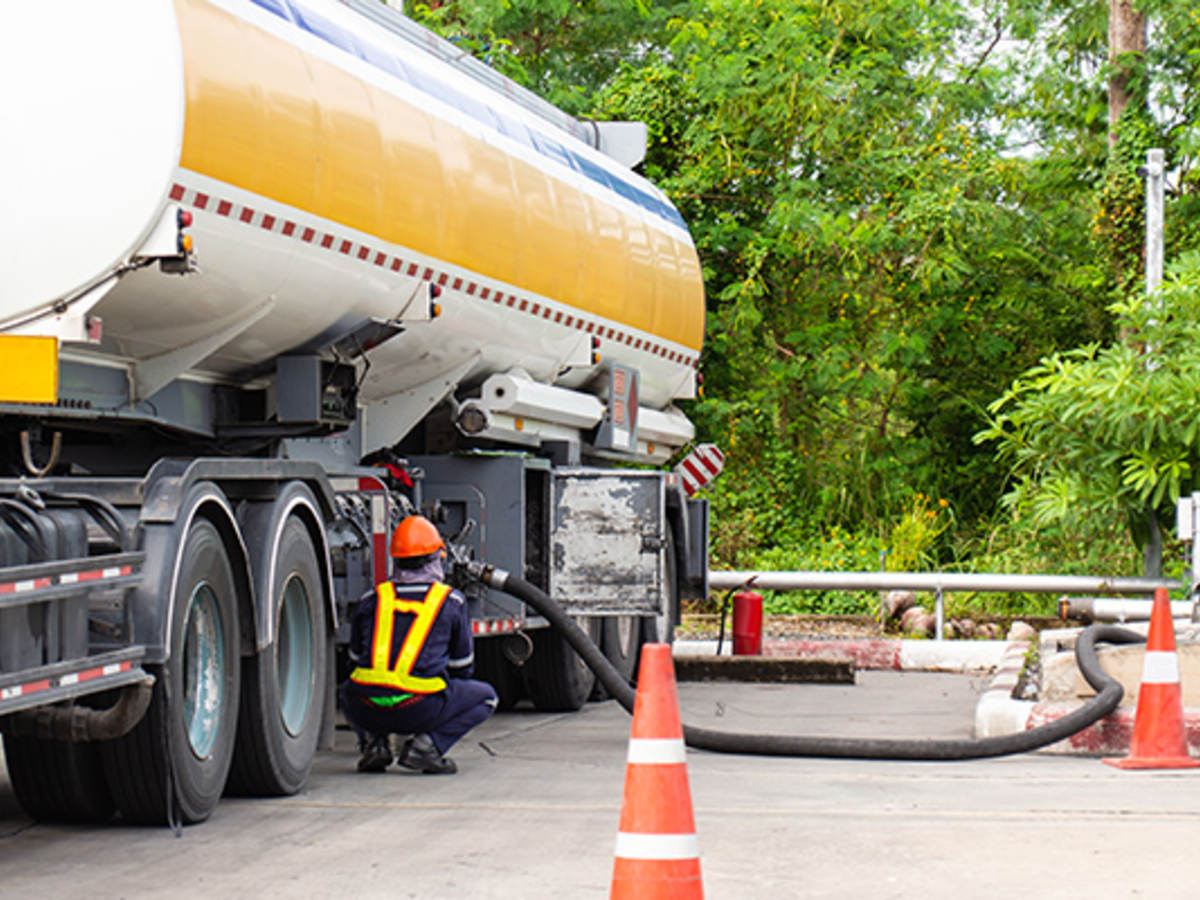 Worker connecting hose to chemical transport truck 