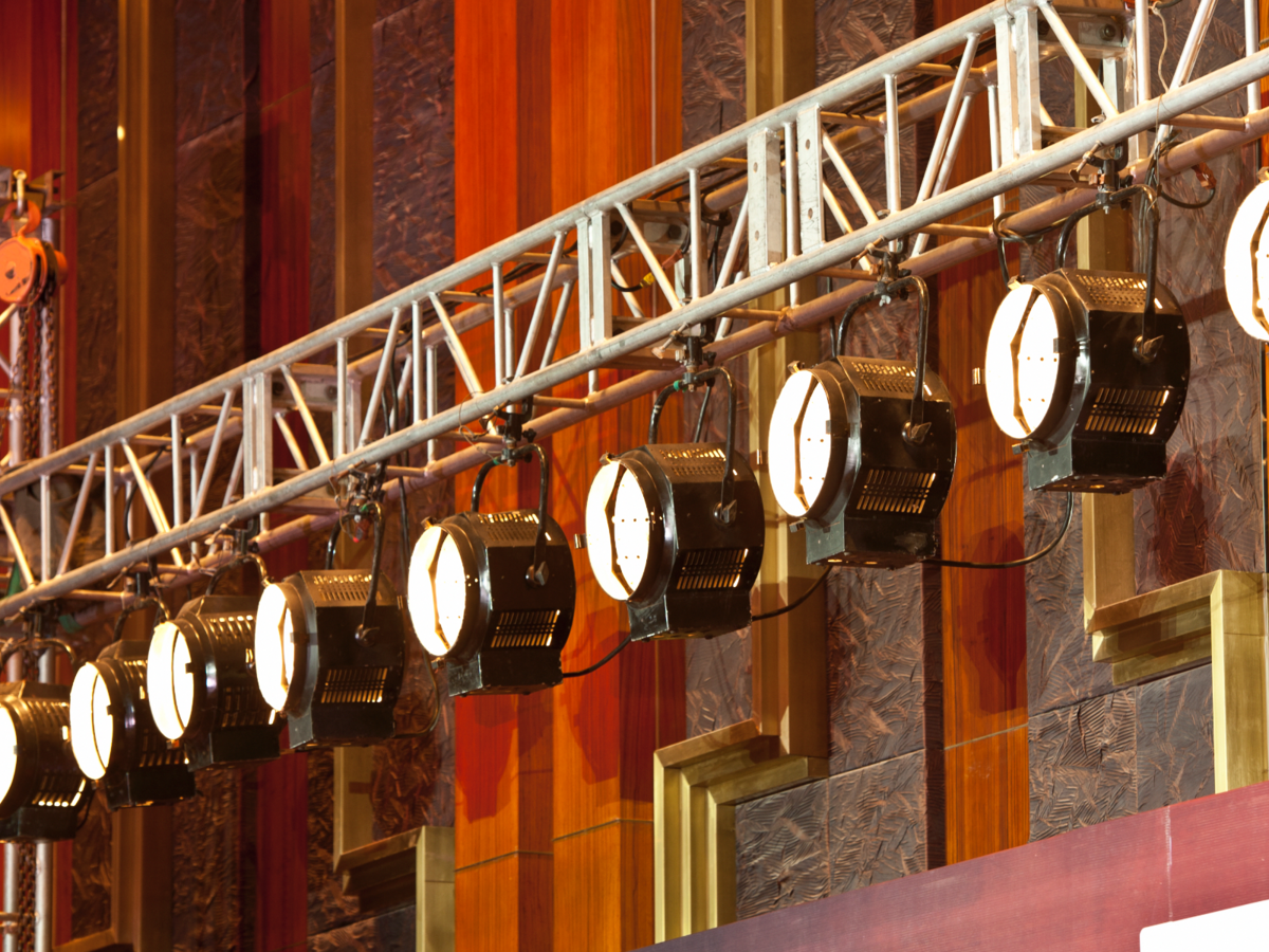 Theater lights hang from backstage scaffolding, ready for the upcoming performance. 