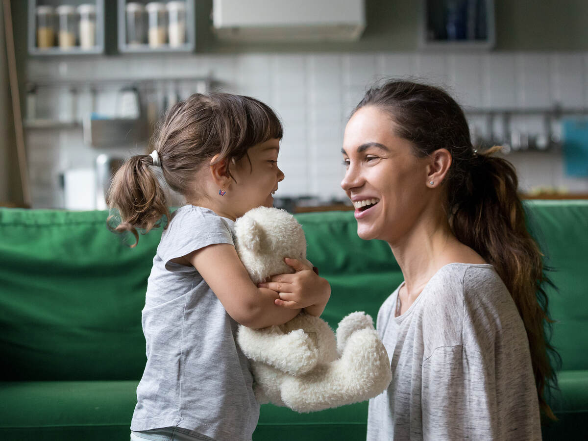 Smiling mother and child playing with stuffed toy