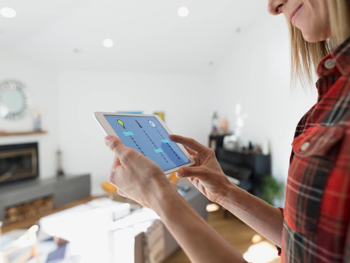 Woman controlling home utilities with digital tablet.