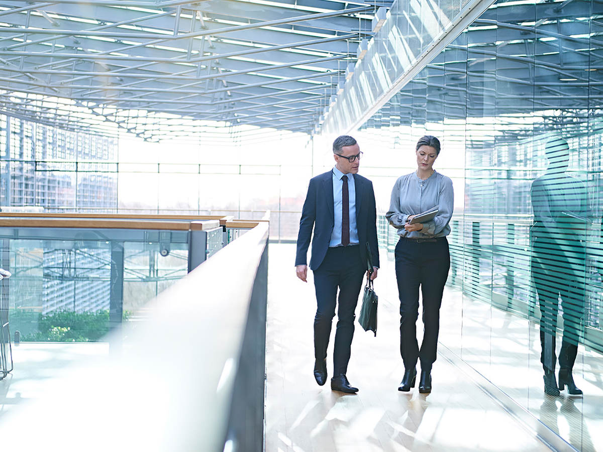 Two employees having a walking meeting in a glass building