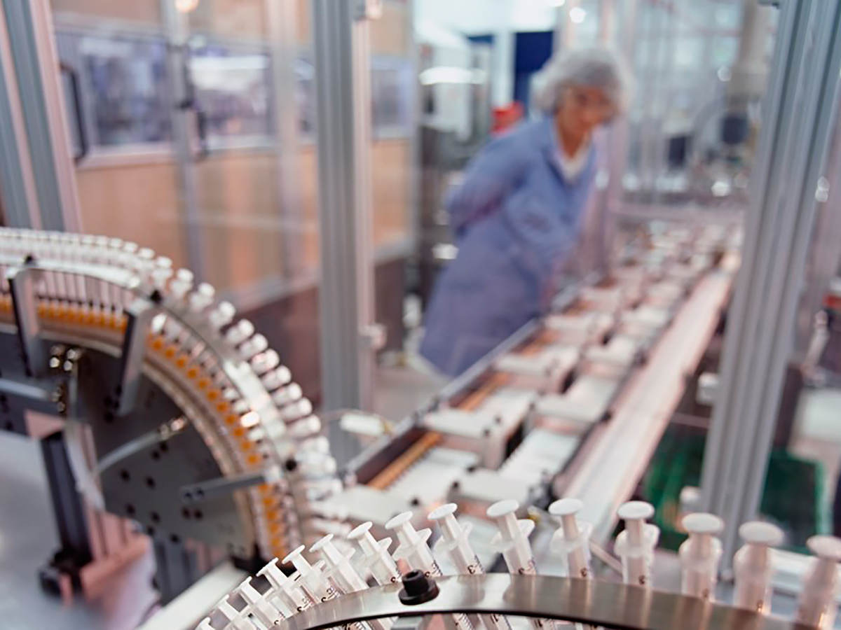 A syringe factory with a worker in the background