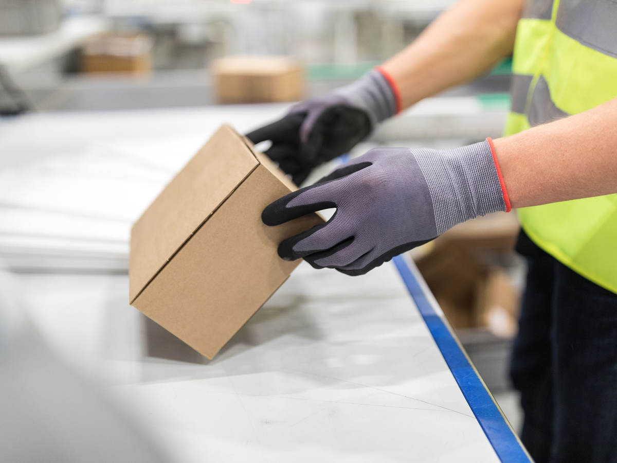 Worker checking package from conveyor belt in warehouse