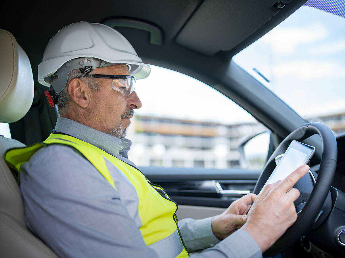 Architect sitting in the car and using a digital tablet.