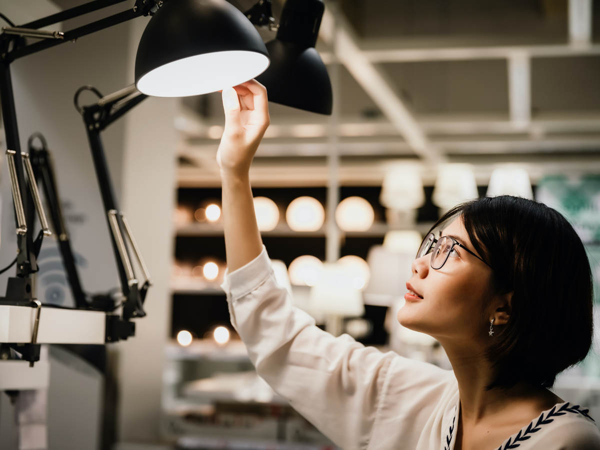 A consumer examines a row of lamps at a retail store.