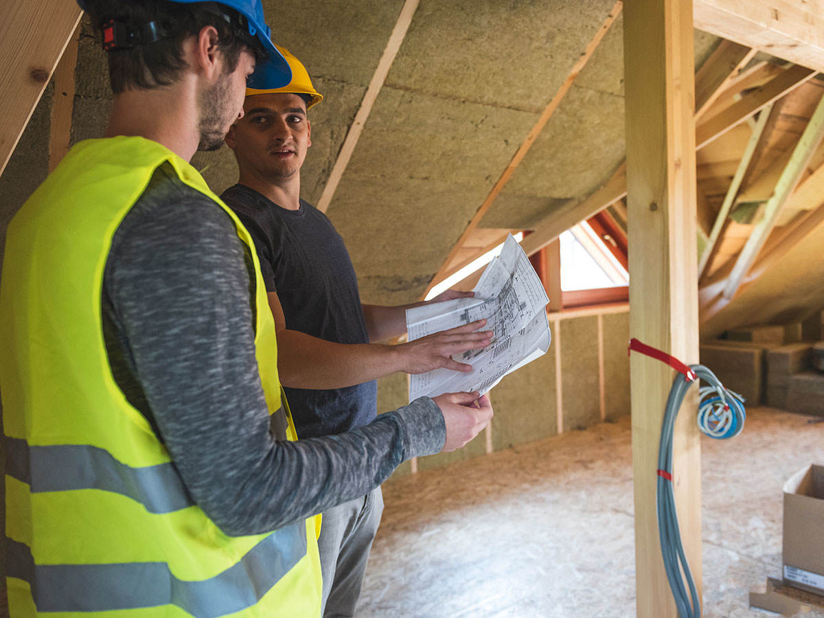 Workers discussing blueprints in an attic