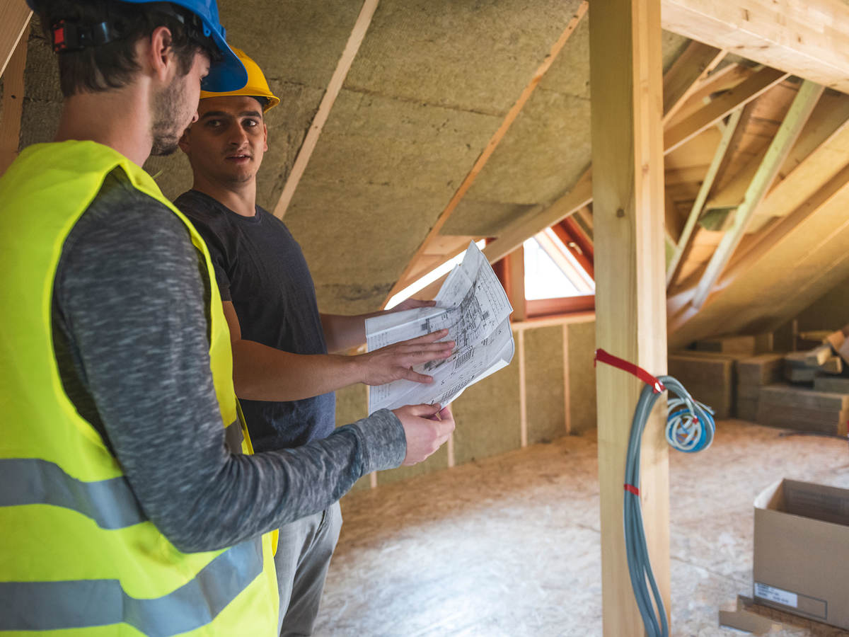 Workers discussing blueprints in an attic