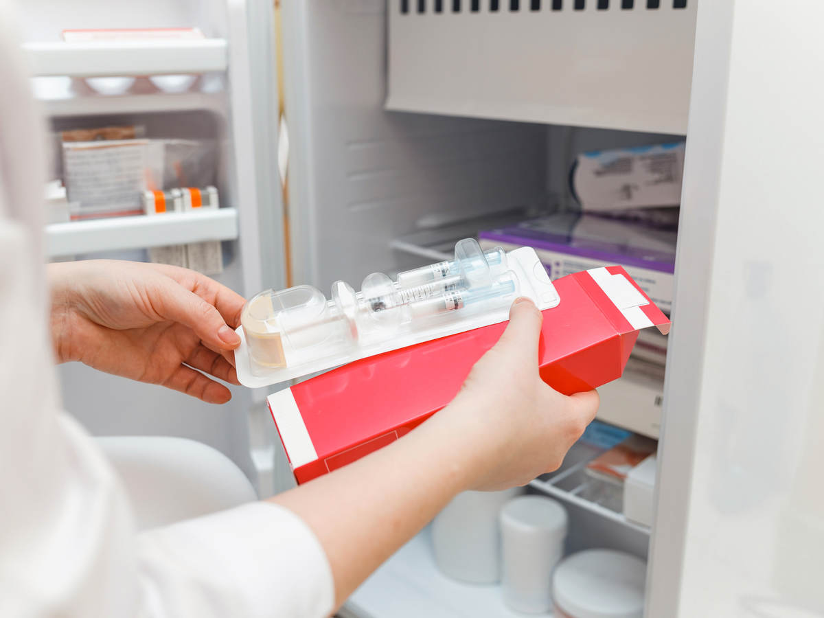 The doctor takes out medicine from the refrigerator with a disposable syringe