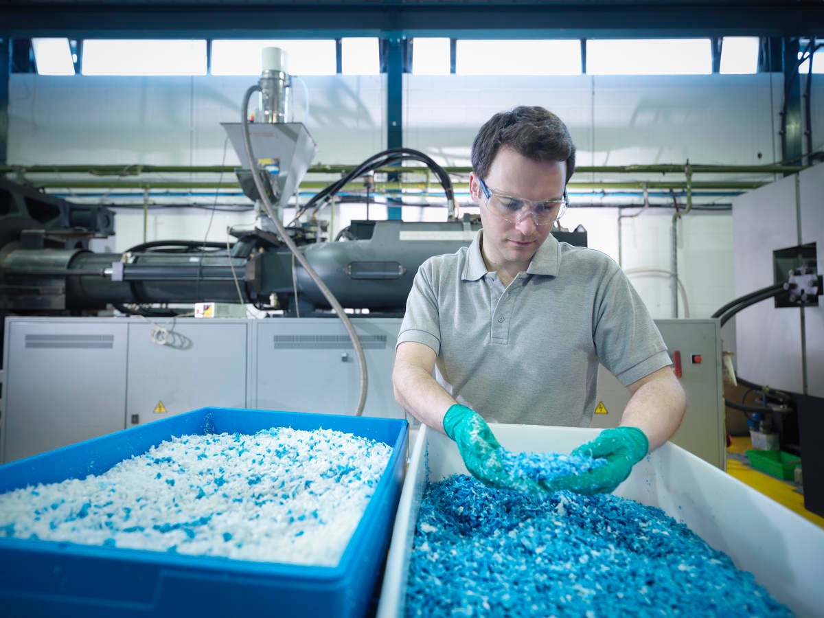 Worker inspecting recycled plastic in plastics factory