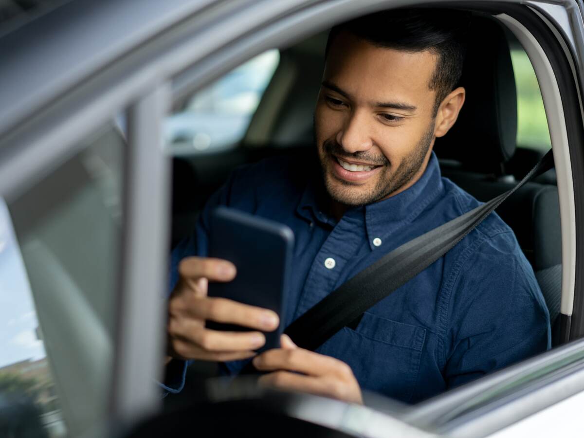 man looking at a mobile phone in car