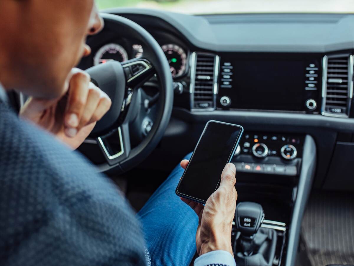 man looking at a mobile phone in car