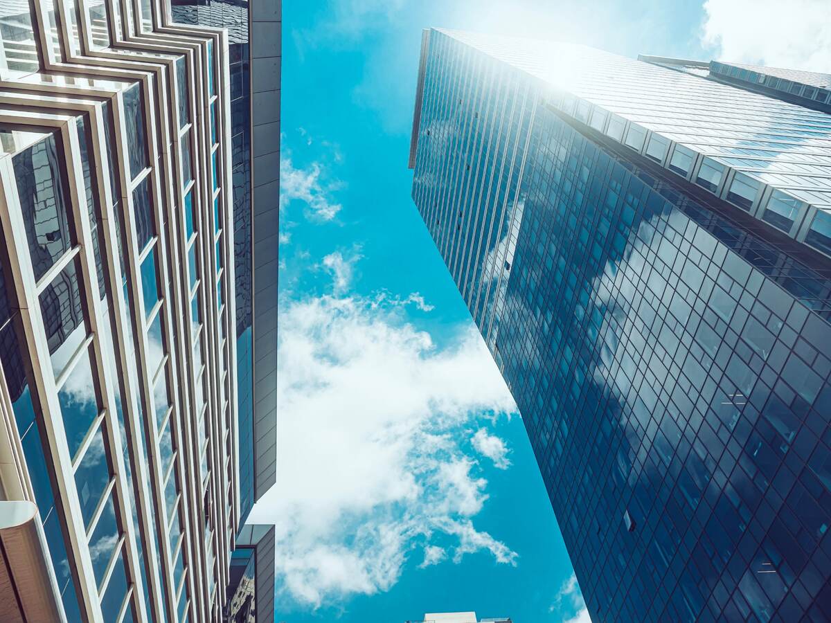 sky with clouds peeking through tall buildings