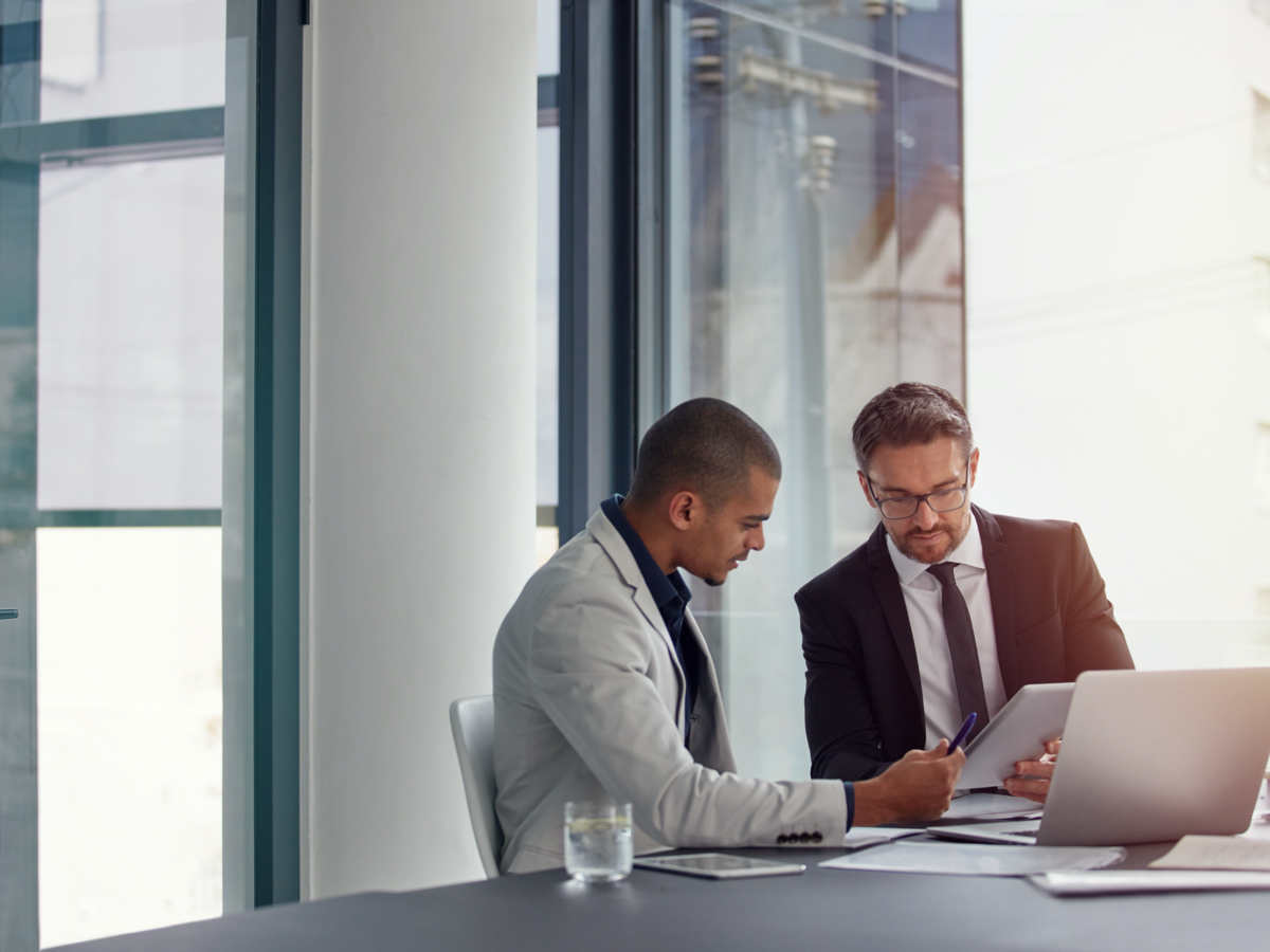 Two people looking at notes in front of a laptop