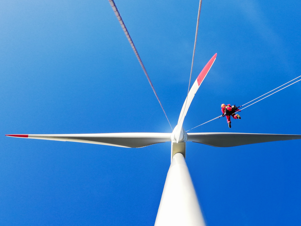 Person climbing up a rope on a wind turbine