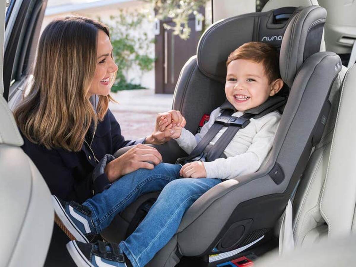Child in car seat with a mom helping buckle in the child