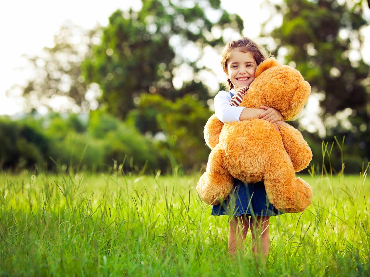 Little girl dancing with her teddy bear in nature