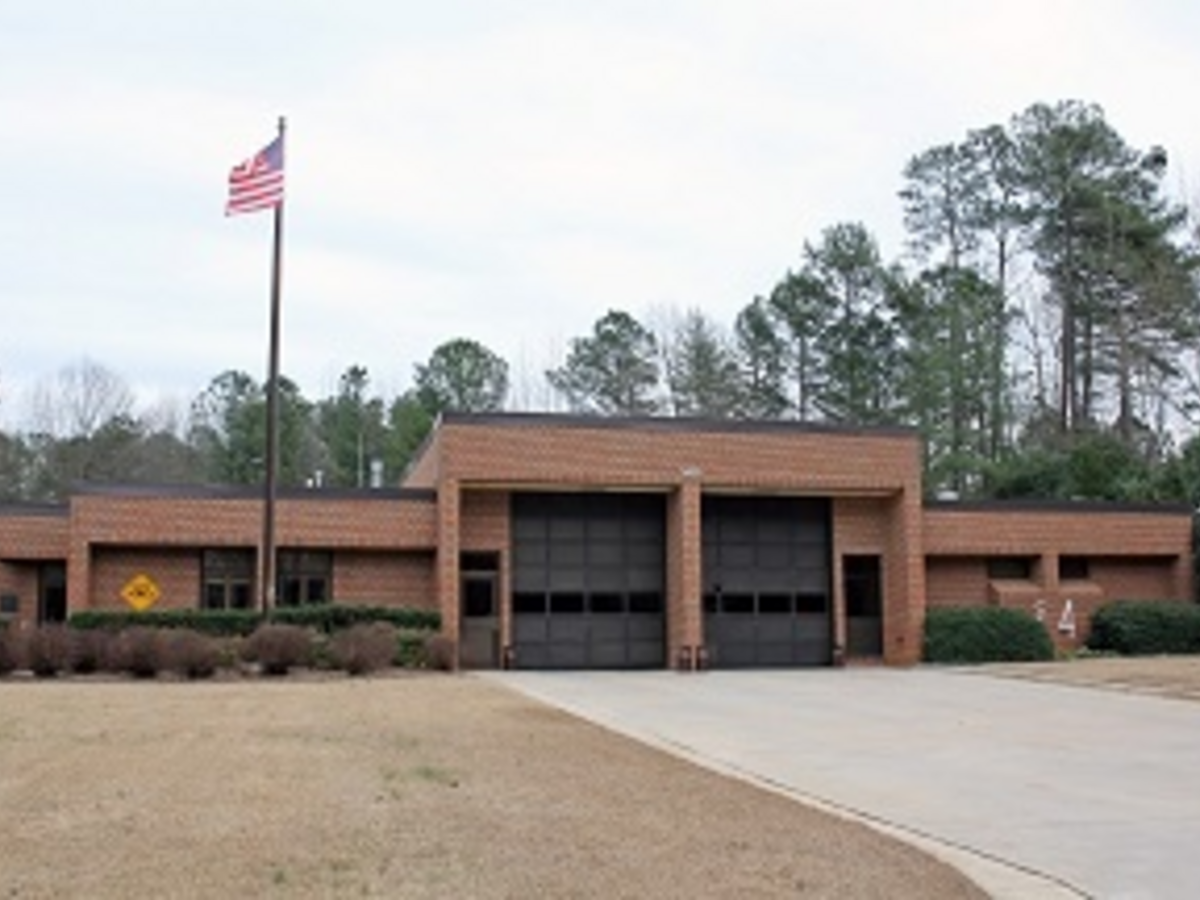 Brown brick firehouse in Cary, North Carolina with two garage bays and the U.S. flag