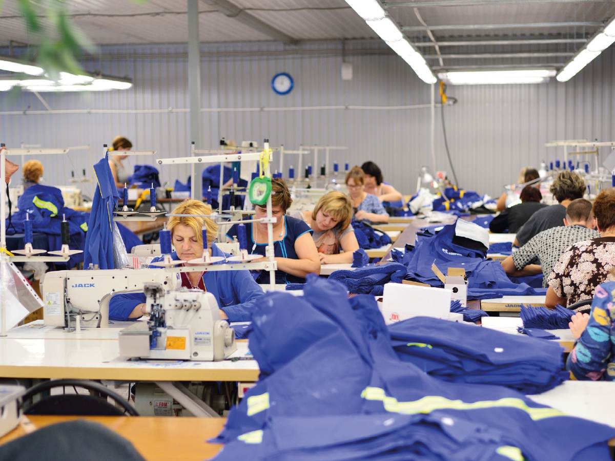 Tailors sewing blue fabric in a factory setting