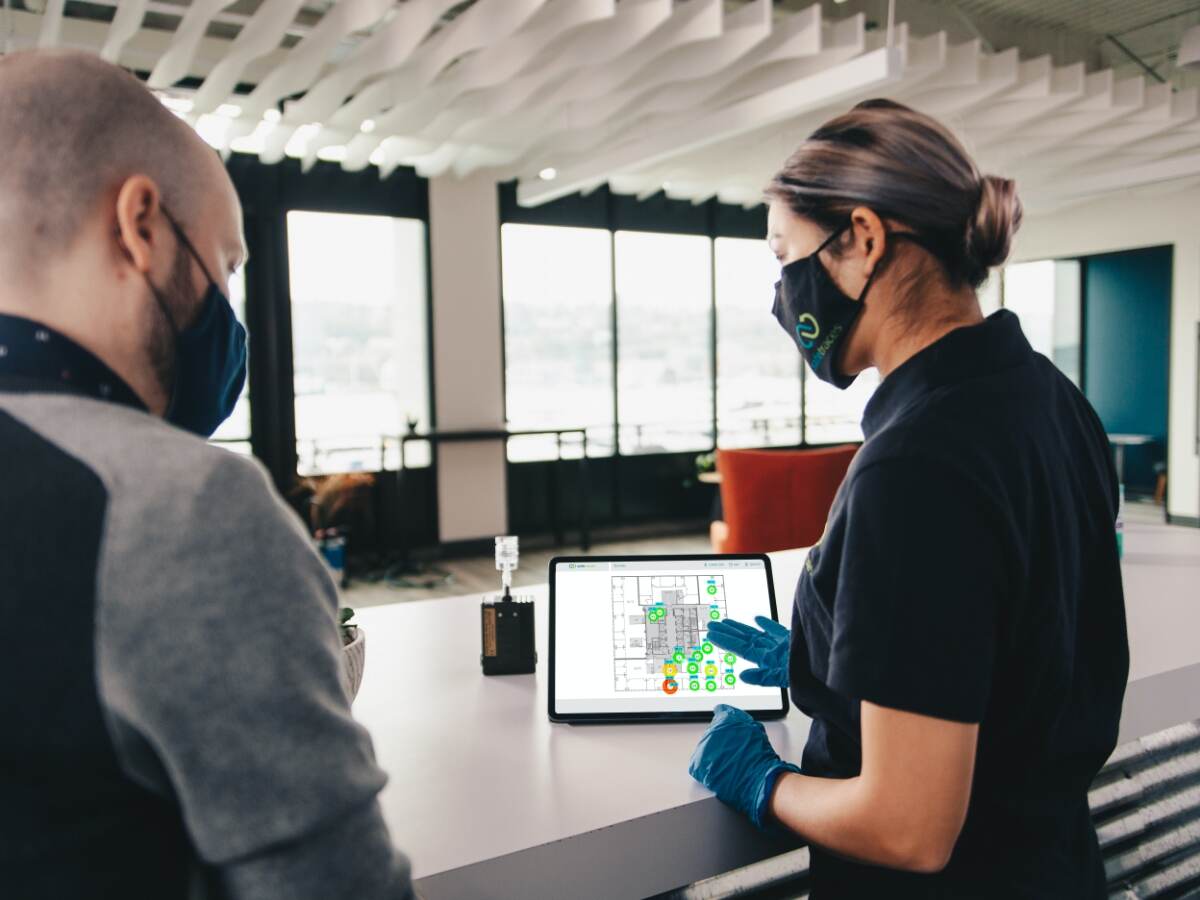 Two masked employees looking at a tablet