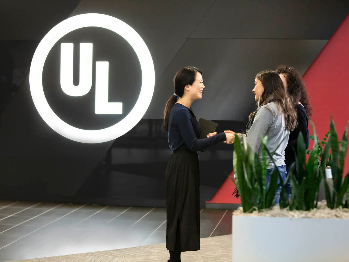 UL’s experts and customer meet in from of an electric sign at UL’s headquarters.