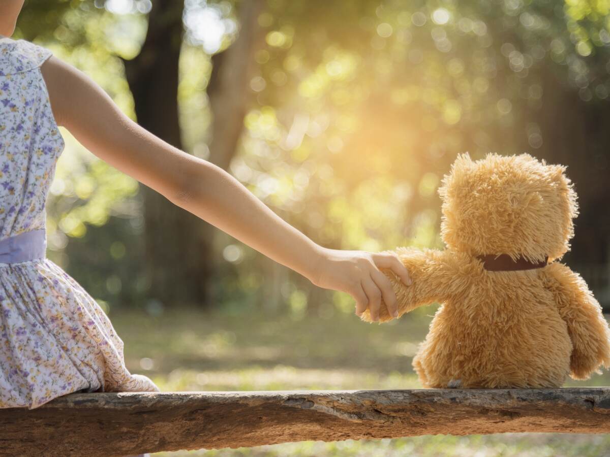 Young girl holding hands with a teddy bear