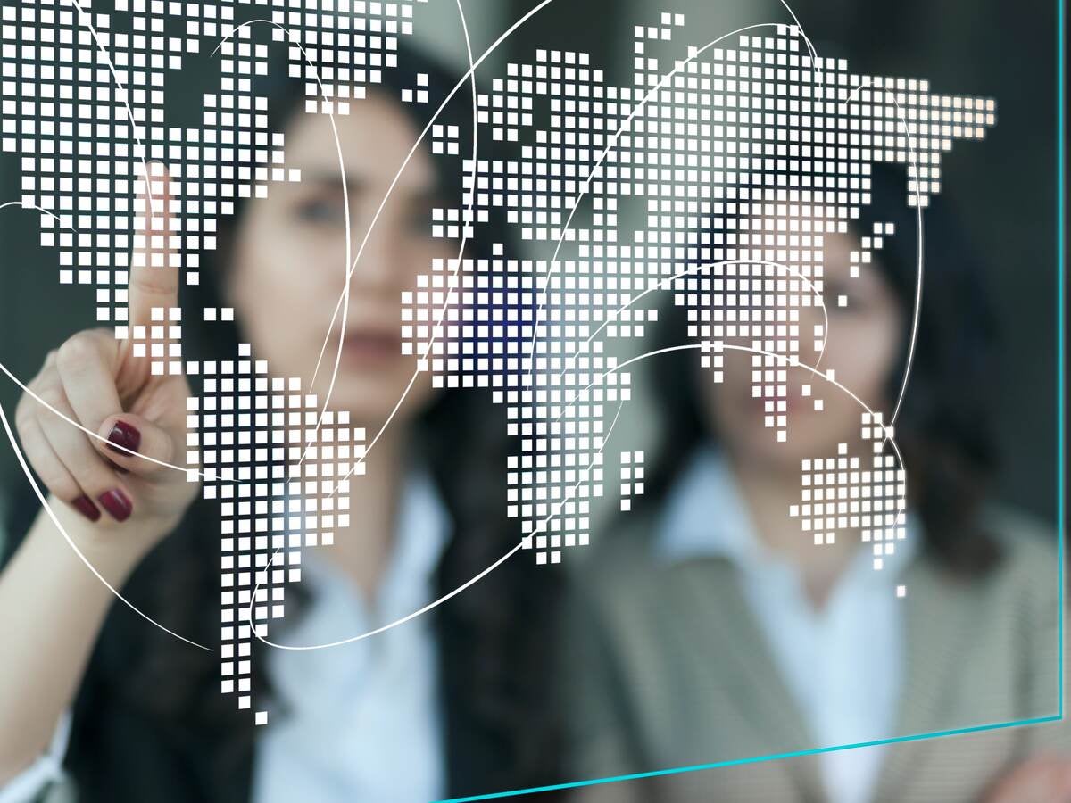 Two business professionals looking at a digital map of the world