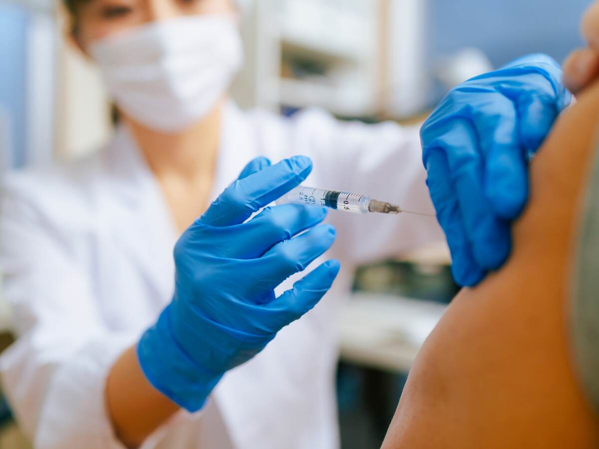 Medical worker wearing blue gloves injecting a patient in the arm