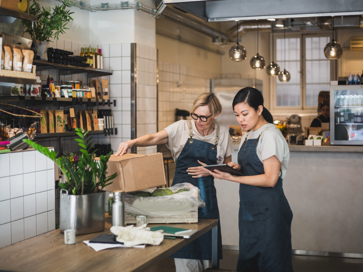 Two people inspecting produce using a tablet, inside a health food restaurant