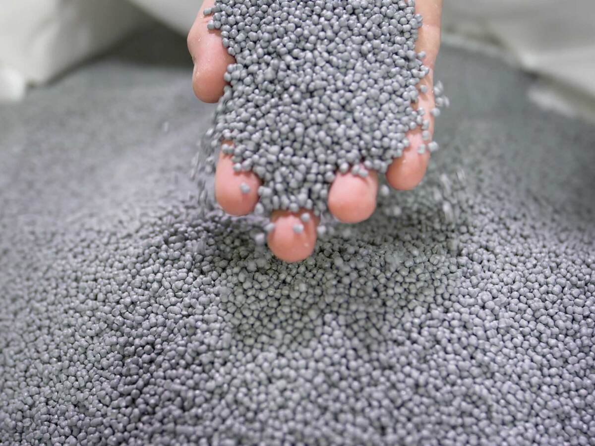 A person's hand holding plastic pellets