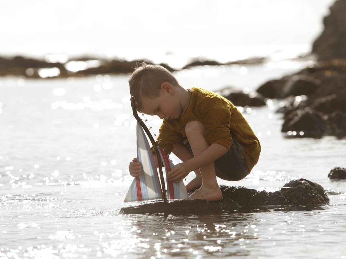 Young boy playing with a toy sailboat