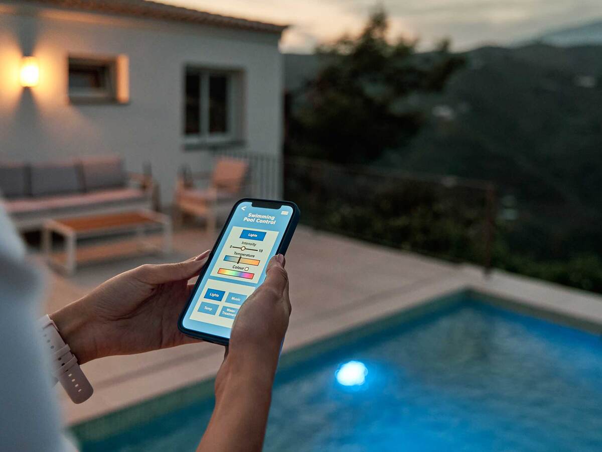 A homeowner uses her mobile device to control the lighting settings of her pool.