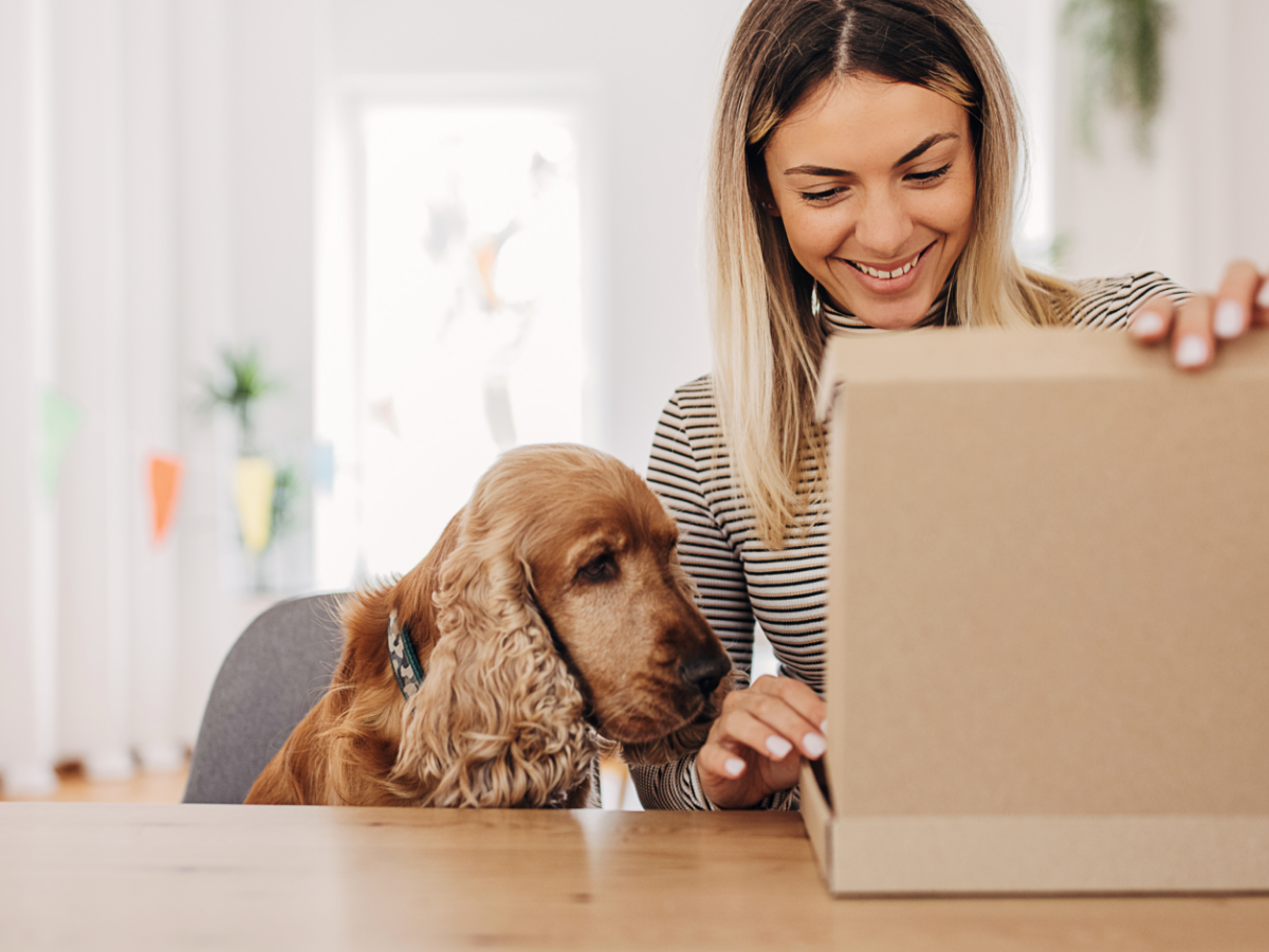 Woman sitting next to her dog while opening a package