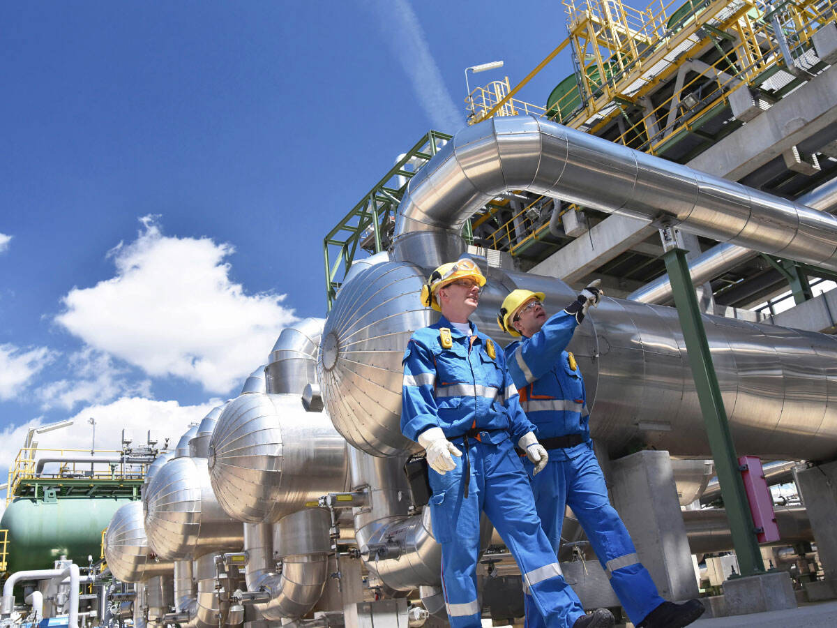 Two workers looking at the outside of a pipe/tank network