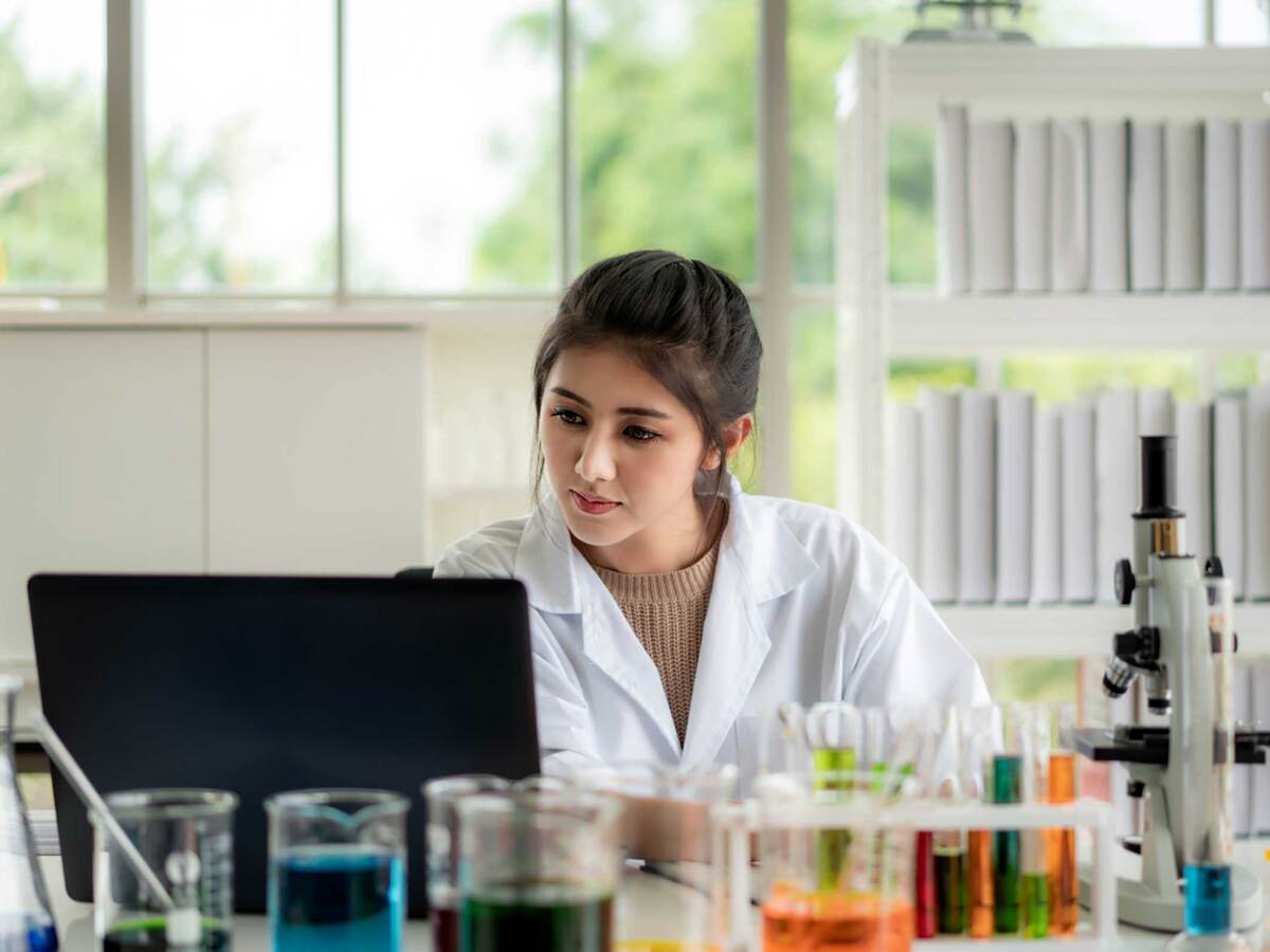 Asian woman scientist student checking results on laptop in laboratory