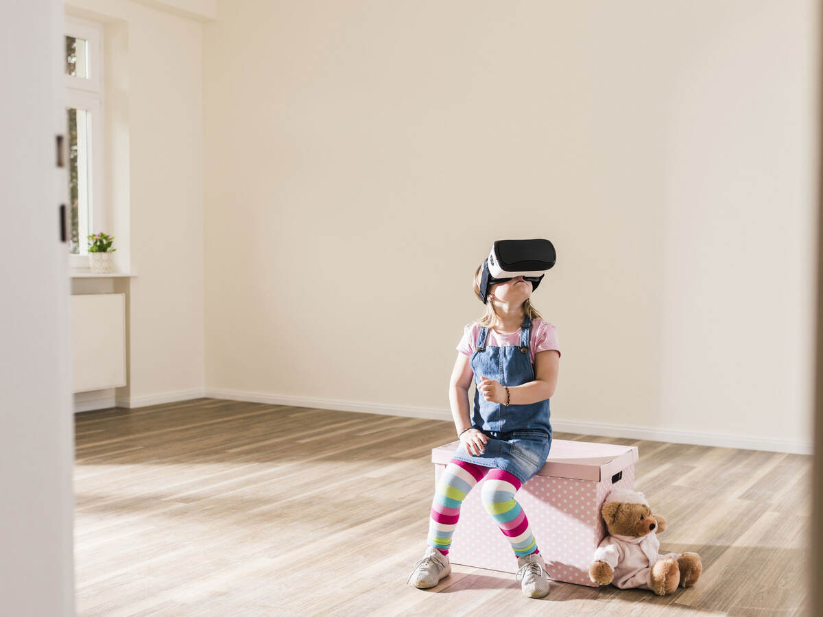 Little girl wearing a VR headset with a teddy bear