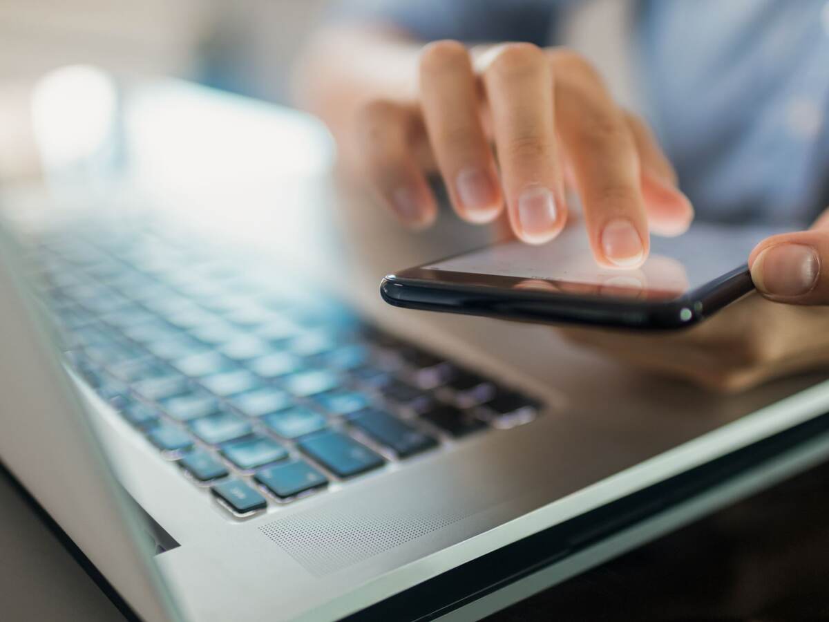 Close-up of a businesswoman using a phone and laptop.