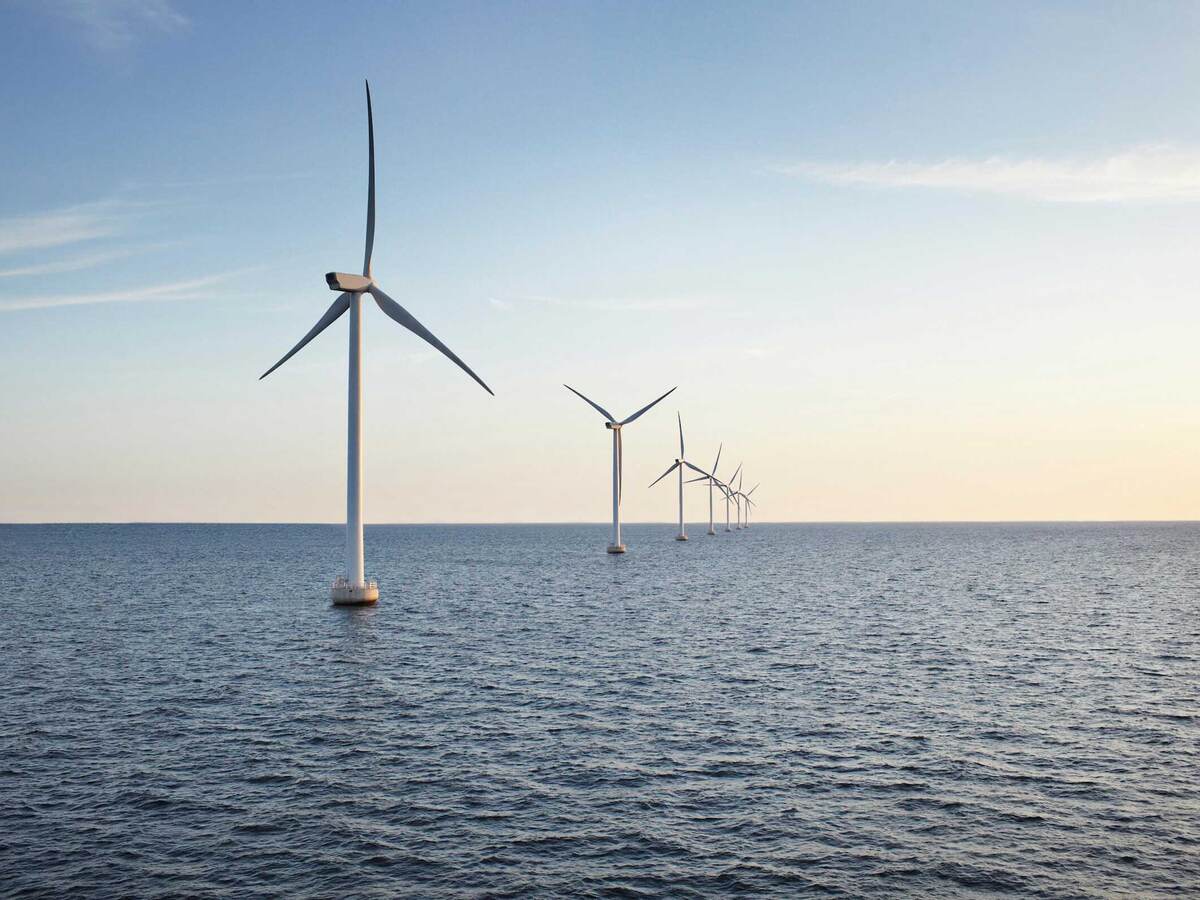 A row of wind turbines stretching across a body of water
