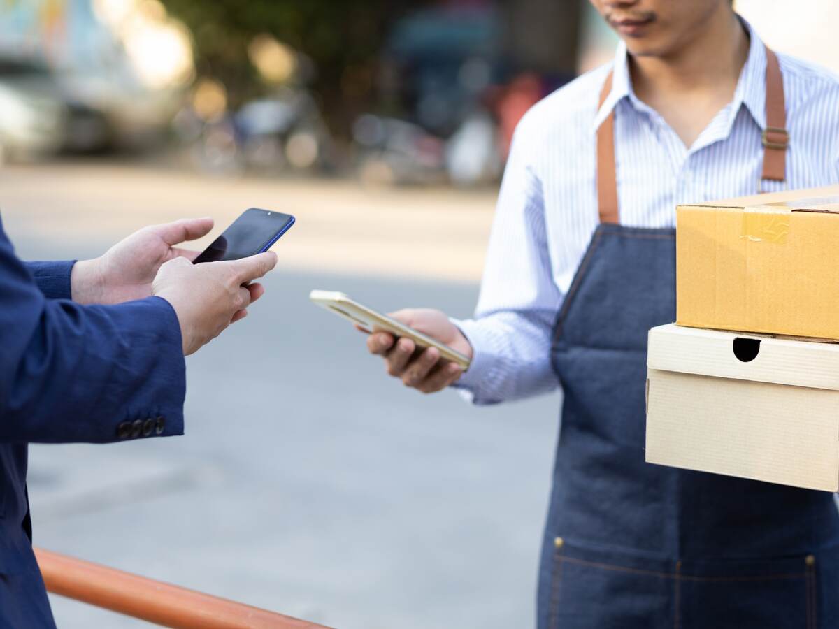 Two men use mobile phones to complete payment for delivery service.